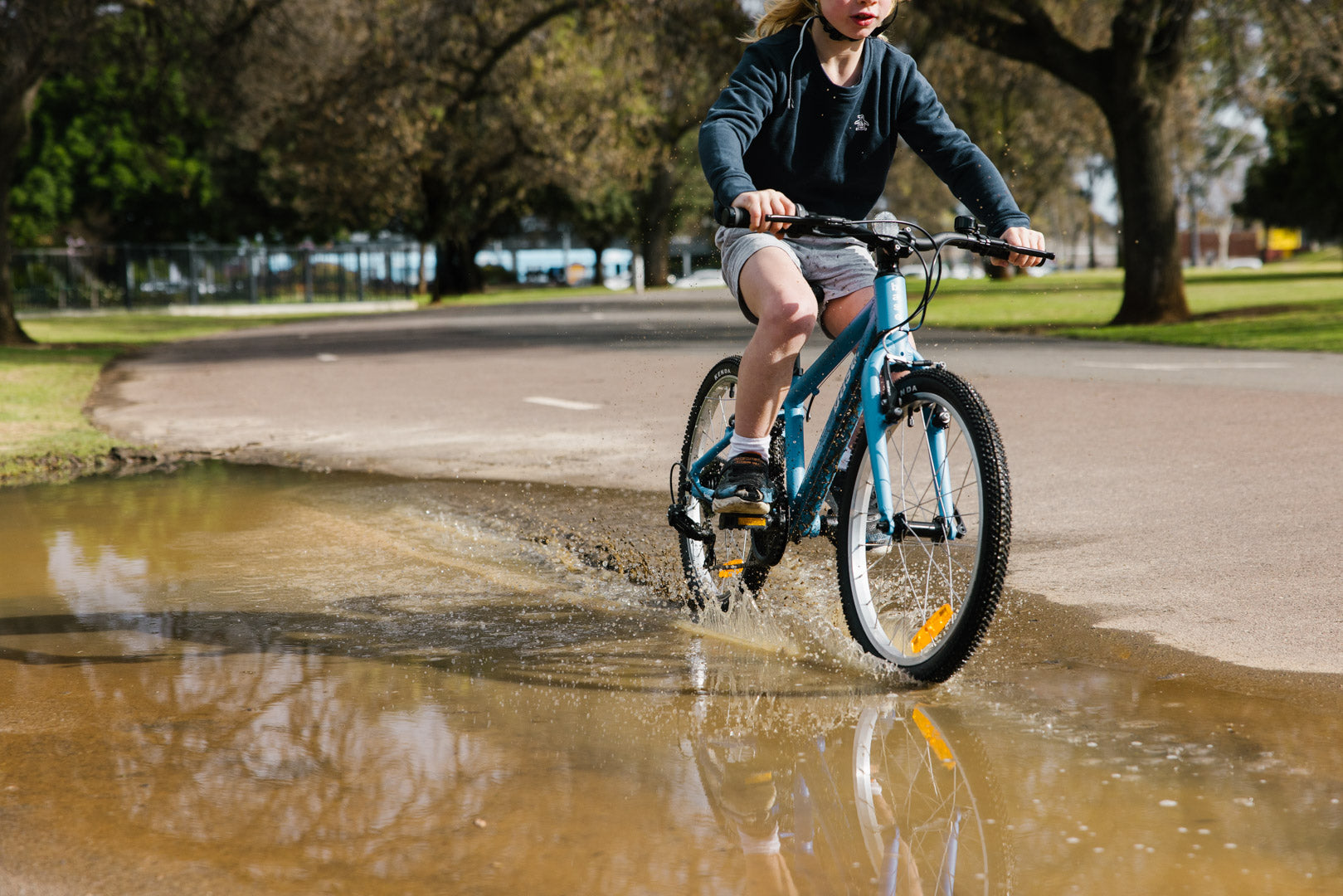 Boy riding through a puddle on his bike making a splash