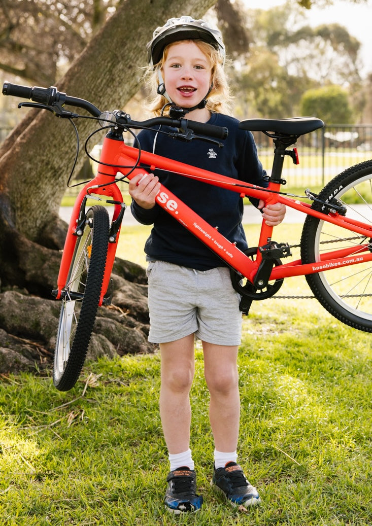Child holding a red bicycle in an outdoor setting