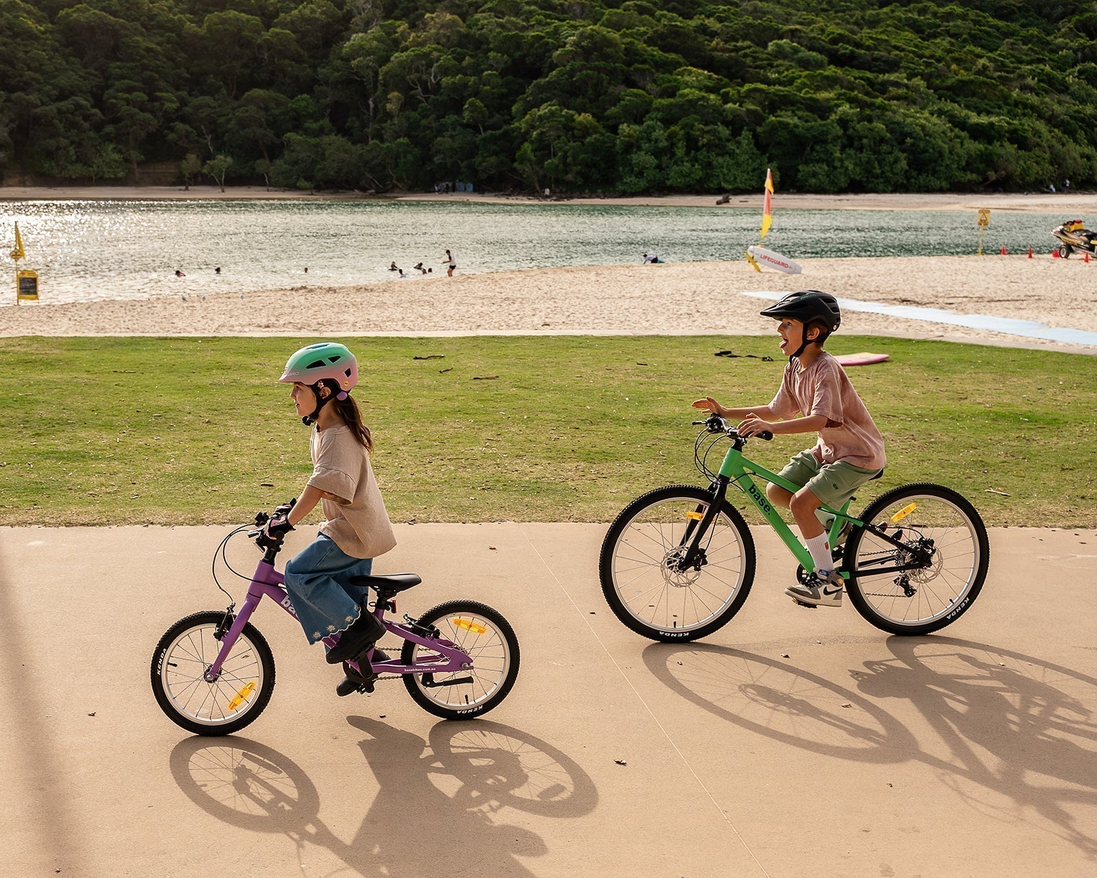 Two kids riding their bikes by the beach
