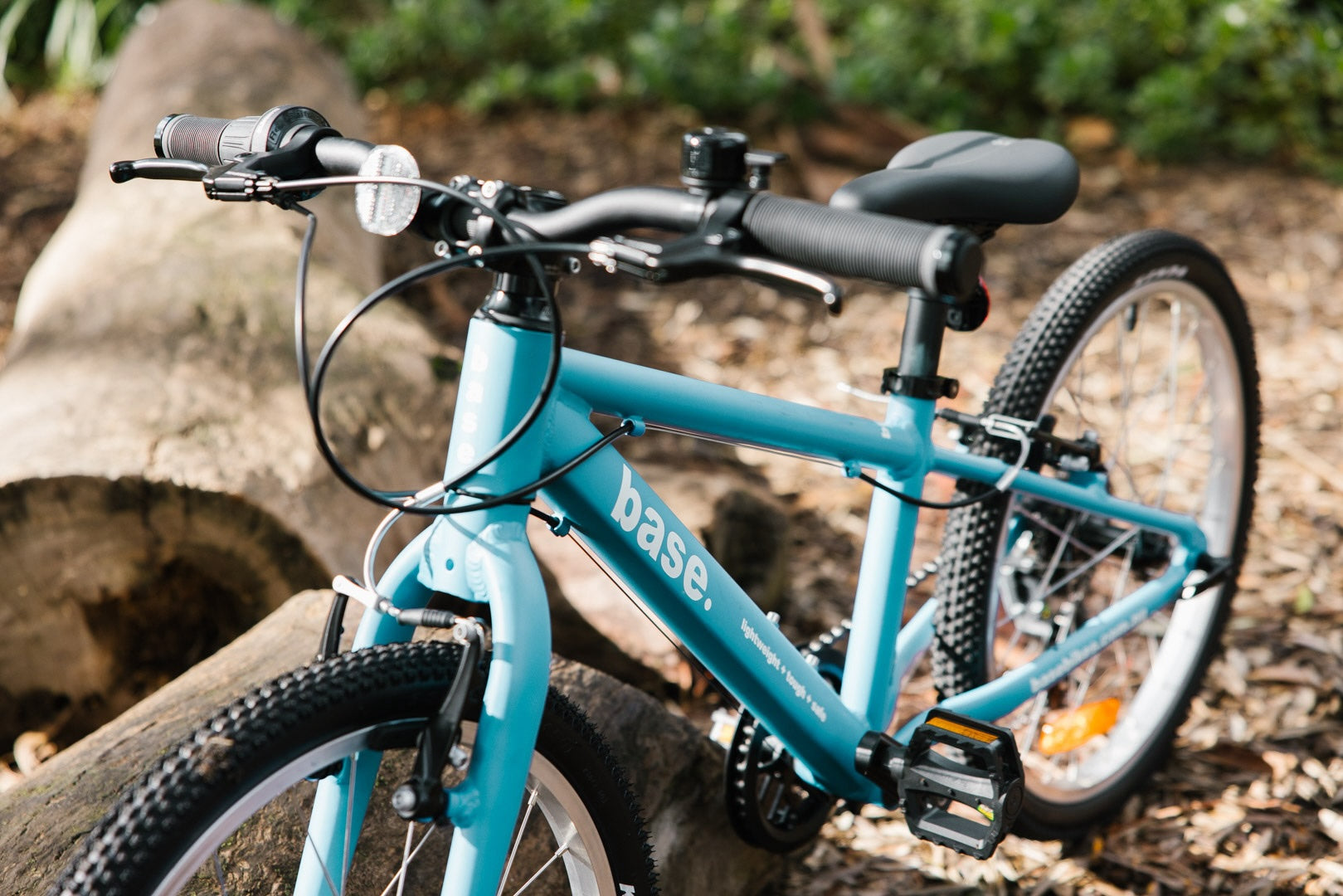 Blue 20 inch bike propped up against a log on a mountain bike trail