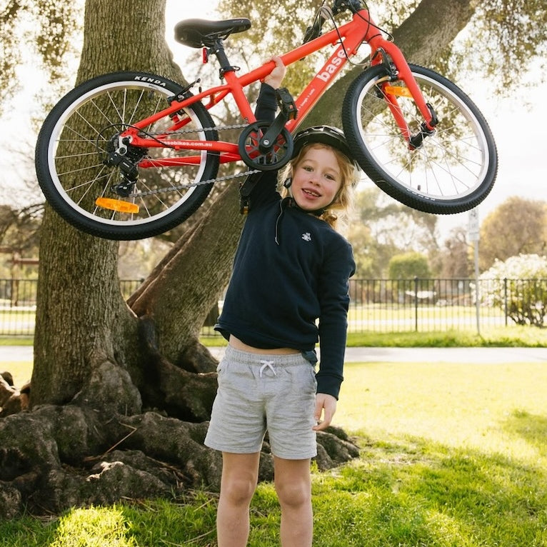 Young boy holding his 20 inch bike above his head to show how light it is