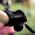A close-up of a person's hand wearing a black Giro fingerless glove while holding a bicycle handlebar, with a blurred outdoor background.