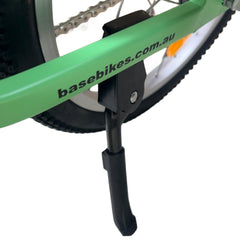 Close-up of a green bicycle with a chain-stay mounted kickstand attached.