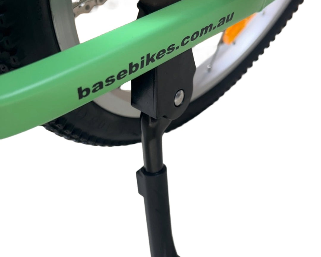 Close-up of a green bicycle with a chain-stay mounted kickstand attached.