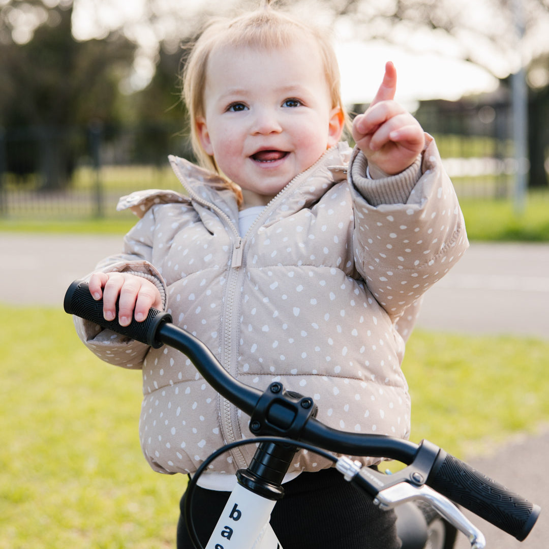 Smiling toddler on a white balance bike