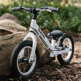 White base balance bike propped up against a log