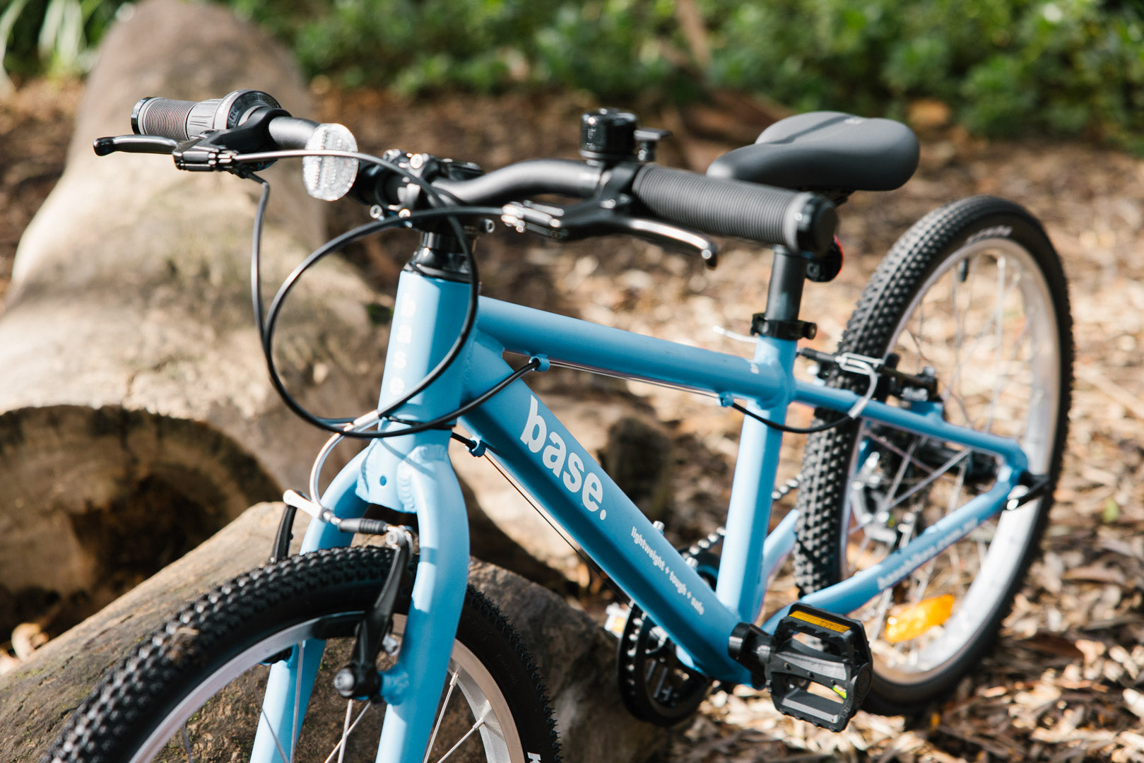 Blue children's bike leaning against a log in a wooded area