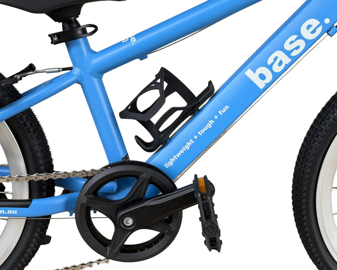 Close-up of a white water bottle with a black cap mounted in a black frame-mounted bottle holder on a bright blue bicycle frame.