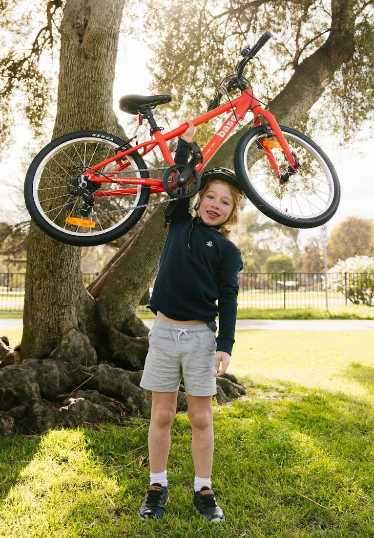 Young boy holding his 20 inch bike above his head to show how light it is